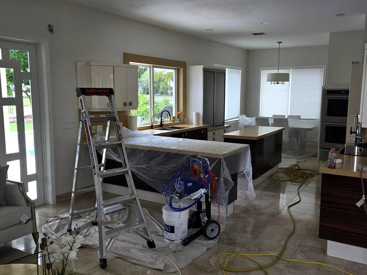Kitchen island, dining furniture and nearby surfaces covered during Ventilocos service