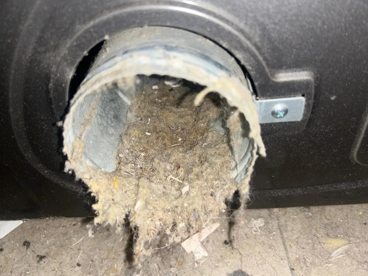 Heavy lint buildup blocking a dryer exhaust connection before cleaning