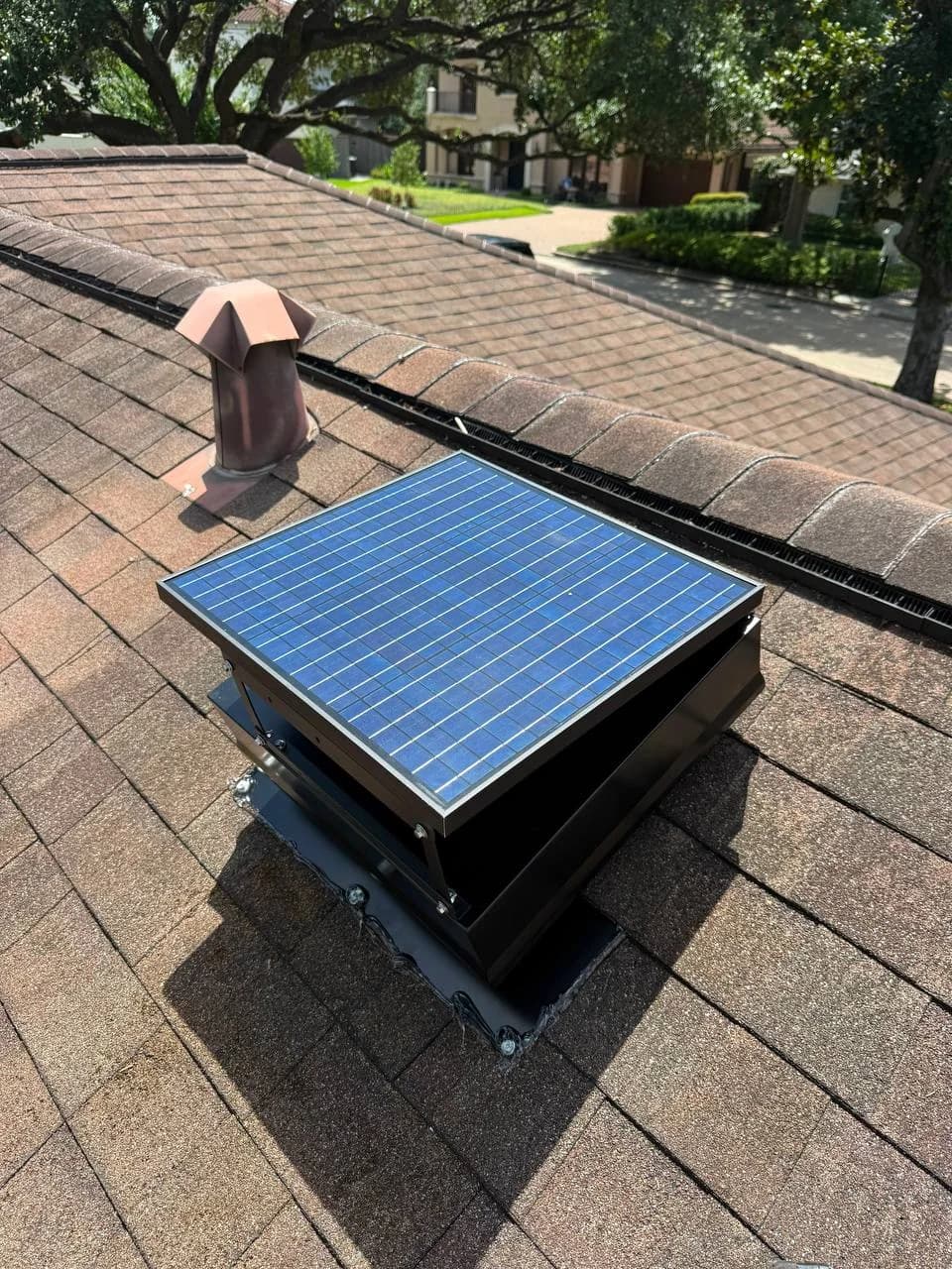 Close-up of a solar attic fan installed on a residential shingle roof